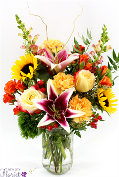 flower arrangement includes lilies, roses, sunflowers, spray roses, snapdragons in a clear mason jar